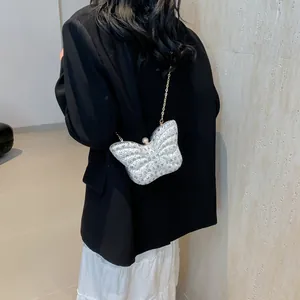 Detalle de bolso de fiesta mariposa plateado con cristales, cierre perla y cadena