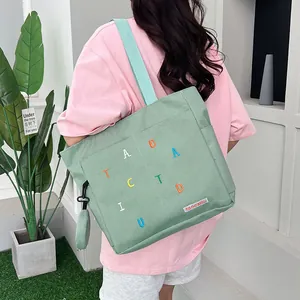 Detail of light green canvas tote bag with colorful letter embroidery and round coin purse