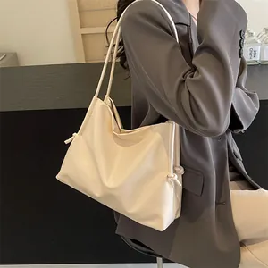 Detalle de bolso tote de cuero suave crema con nudos decorativos y correas delgadas