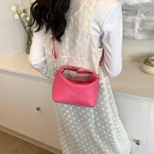 Detail of hot pink shoulder bag with embossed texture and gold metal hardware