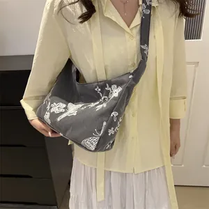 Detail of grey canvas shoulder bag featuring intricate white butterfly and floral embroidery