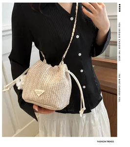 Detail of woven straw bucket bag with gold chain strap and drawstring closure shown on model