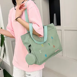 Mint green canvas tote bag with embroidered letters and small round coin purse charm