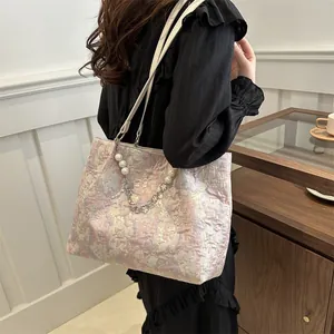 Detail of pink floral jacquard tote bag with decorative pearl and silver floral chain
