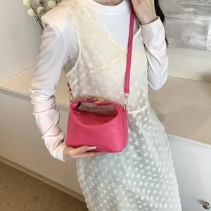Detail shot of pink crossbody bag showing rich rabbit embossed logo and golden hooks