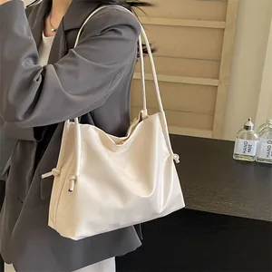 Detalle de bolso tote color crema en piel suave con nudos de cordón y correas finas