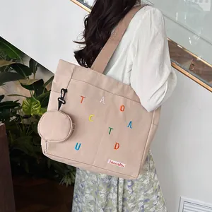 Detail of beige canvas tote with colorful embroidery and a side round hanging pouch