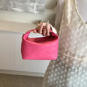 Close-up of pink mini handbag with rich rabbit embossed lettering and gold hardware