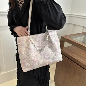Pink and gold textured jacquard tote bag with decorative pearl chain on model shoulder