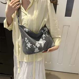 Detailed view of gray canvas tote bag with butterfly embroidery and adjustable strap
