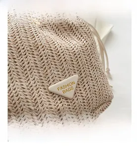 Macro shot of the woven texture and beige triangular logo plaque on this bucket bag