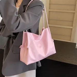 Bolso tote rosa minimalista al hombro con textura suave y detalles de nudos