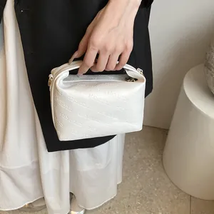 Close-up of white crossbody bag featuring rich rabbit embossed pattern and gold hardware