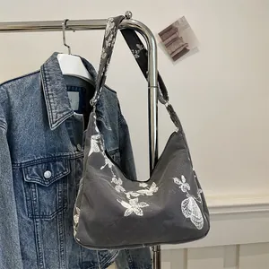 Detailed close-up of butterfly embroidery and texture on dark grey canvas hobo bag