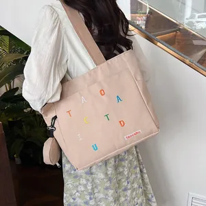 Detail view of beige canvas tote with brown straps and matching round coin purse pouch