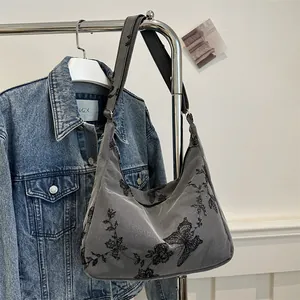 Detail of grey hobo bag featuring intricate butterfly embroidery and wide shoulder strap