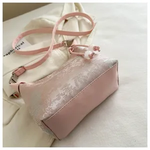 Detailed view of pink jacquard fabric with floral patterns and bead drawstring on handbag