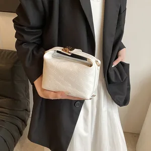 Close-up of rich rabbit embossed texture and gold buckle on white faux leather handbag