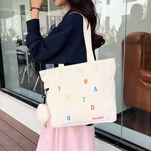 Detail of off-white canvas tote bag with colorful embroidery and matching coin purse