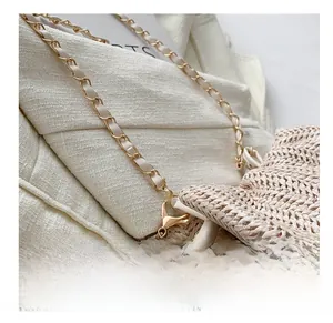 Detailed close-up of woven bucket bag featuring gold chain strap and plush ball charm