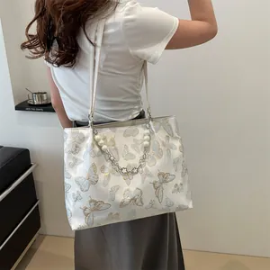 Detail of floral butterfly embroidery and pearl chain on white shoulder tote bag