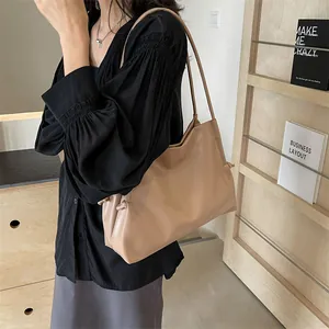Detalle del bolso tote de cuero suave beige con nudos laterales y correas de hombro