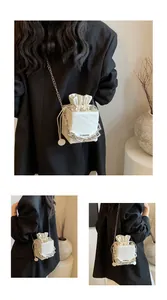 Λεπτομέρεια λευκής τσάντας bucket με ανάγλυφο Rich Rabbit και μεταλλική αλυσίδα