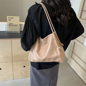 Detalle de un bolso tote de cuero sintético caqui suave con nudo lateral y asas finas