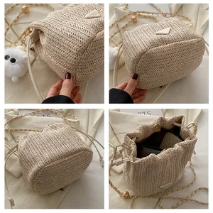 Detail view of woven straw bucket bag with gold chain strap and plush keychain