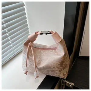Detail of pink silk jacquard handbag with traditional landscape pattern and metal clasp