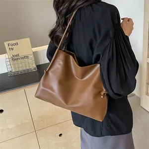 Detalle de bolso tote marrón suave con elegante textura plisada y nudo decorativo