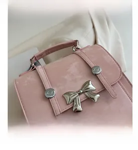 Macro detail of pink faux leather handbag featuring a large silver metal bow ornament