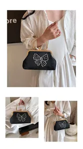 Détail d'un sac de soirée noir avec papillon perlé et anse à perles dorées