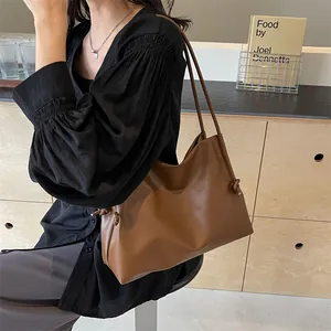 Vista detallada de un bolso tote de cuero suave marrón con diseño elegante de nudo lateral