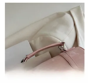 Close-up of pink faux suede handbag handle with silver metal hooks and stitching