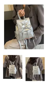 Close-up of a silver bow backpack featuring metallic finish and lace-up details on the flap
