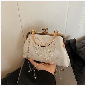 Détail du sac de soirée en satin blanc avec motifs perles papillon et fermoir doré