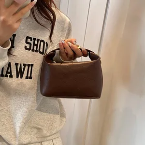 Detail of deep brown crossbody bag with rich rabbit embossed pattern and gold hardware