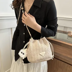 Detail shot of straw bucket bag featuring woven texture and cute plush charm accessory