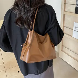 Vista de detalle de bolso tote de cuero marrón con nudos laterales y textura suave