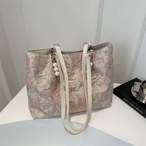Detail of pink-gold jacquard fabric tote with pearl charm and white PU handles