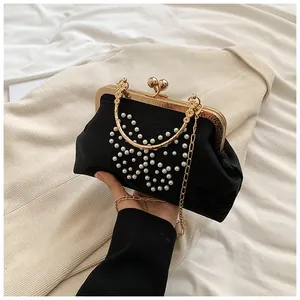 Détail du sac coquille en velours noir avec nœud en perles et cadre en métal doré