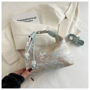 Detail of light blue brocade handbag featuring golden landscape patterns and bead drawstring