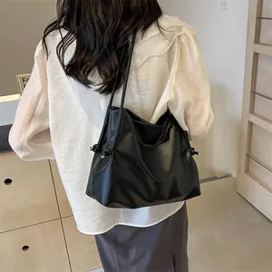 Vista posterior de modelo con bolso tote minimalista de cuero negro y detalles de cordón
