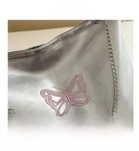 Detail shot of silver quilted chain bag with pink butterfly embroidery and metal zipper