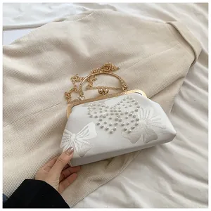Détail du sac de soirée blanc avec broderie papillon en perles et fermoir doré chic