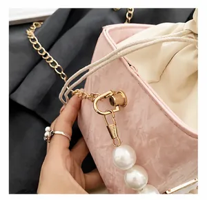 Detail shot of pink bucket bag with gold hooks, large pearls and woven drawstring closure