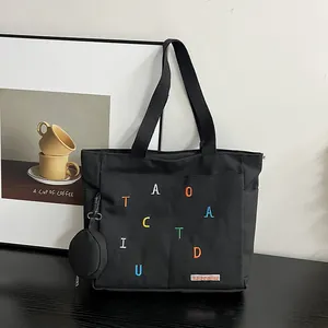 Detail of black canvas tote bag with rainbow embroidery and detachable coin purse pouch