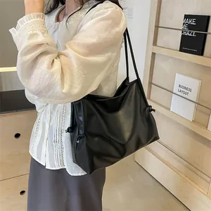 Detalle de bolso tote de cuero negro suave con nudos laterales y correas delgadas