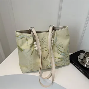 Detail of light green jacquard tote with bamboo pattern, pearl charms and silver chain